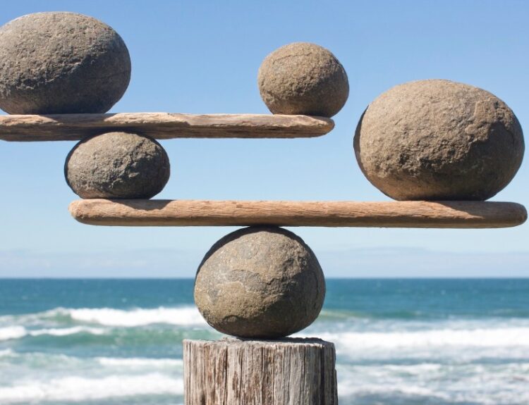 A balance structure made of rocks and wood against a seaside background