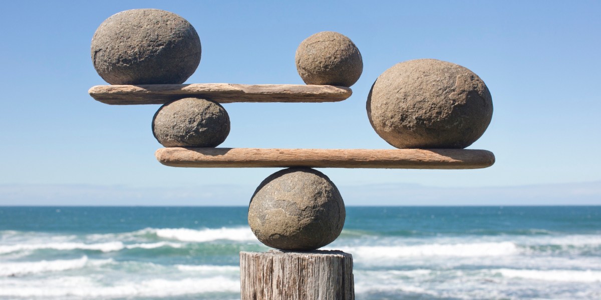 A balance structure made of rocks and wood against a seaside background